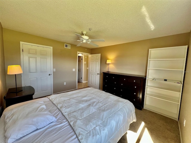 bedroom with ceiling fan, light carpet, and a textured ceiling