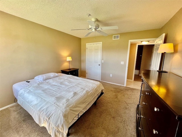 bedroom with ceiling fan, light carpet, and a textured ceiling