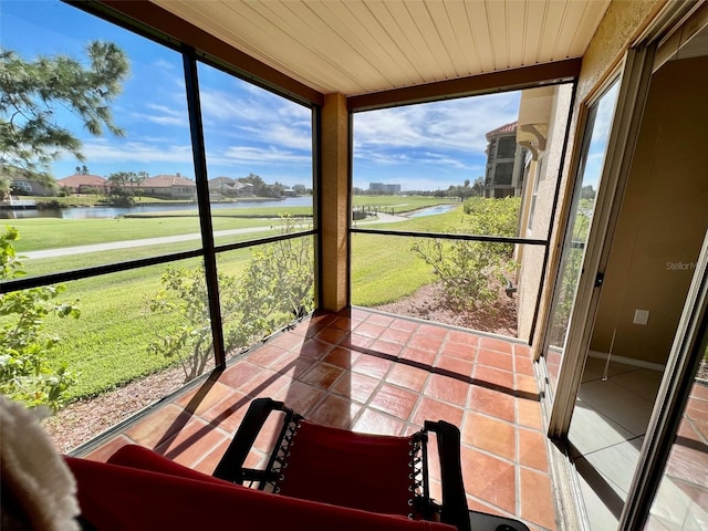 sunroom featuring a water view and wooden ceiling