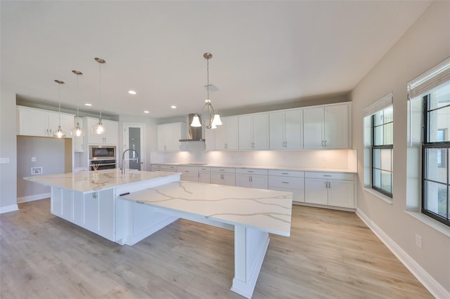 kitchen with wall chimney exhaust hood, backsplash, white cabinets, and stainless steel appliances