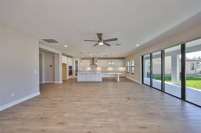 unfurnished living room with recessed lighting, visible vents, light wood-style flooring, a ceiling fan, and baseboards