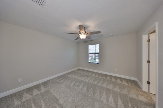 empty room with light carpet, a textured ceiling, visible vents, and baseboards