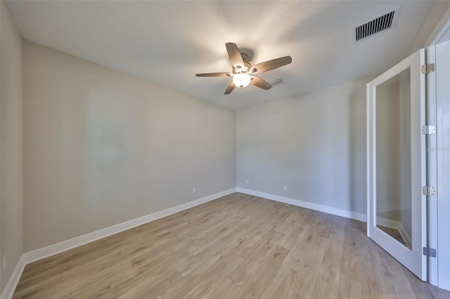 empty room featuring ceiling fan, light wood finished floors, visible vents, and baseboards