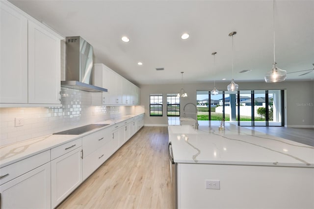 kitchen with decorative backsplash, a large island, wall chimney exhaust hood, black electric cooktop, and a sink