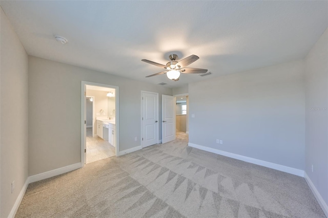 unfurnished bedroom with light carpet, a ceiling fan, visible vents, baseboards, and ensuite bath