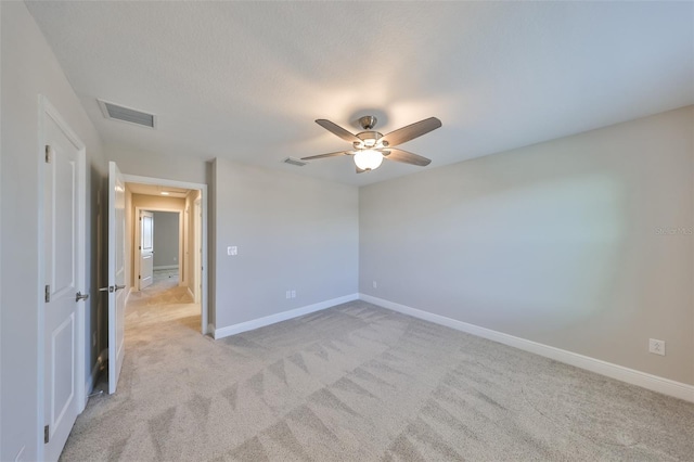 unfurnished room featuring light carpet, ceiling fan, visible vents, and baseboards