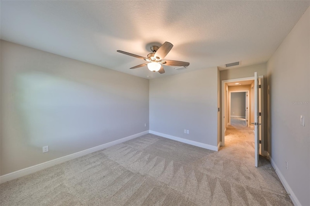 empty room with light carpet, baseboards, visible vents, and a ceiling fan