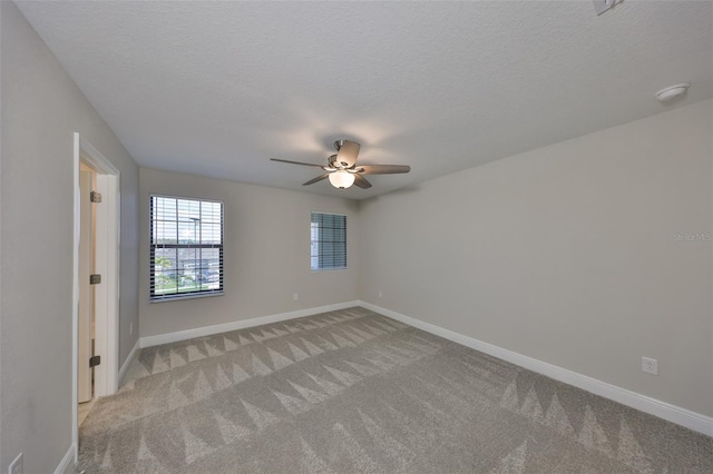 empty room featuring ceiling fan, baseboards, a textured ceiling, and light colored carpet