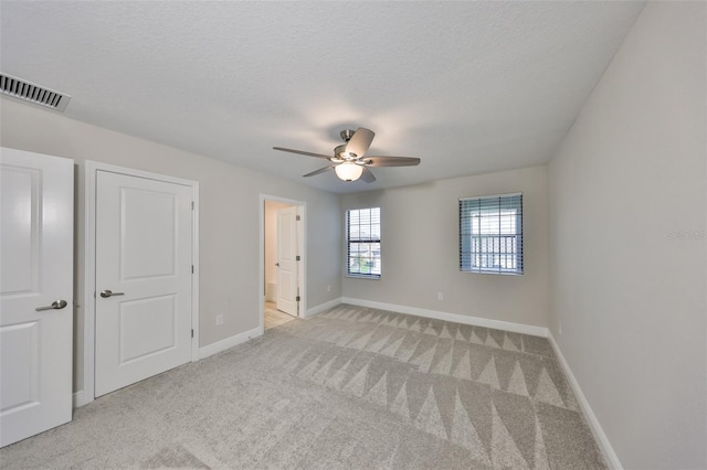 unfurnished bedroom featuring light carpet, baseboards, visible vents, and a textured ceiling