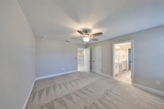 unfurnished bedroom featuring visible vents, ensuite bathroom, light carpet, a textured ceiling, and baseboards