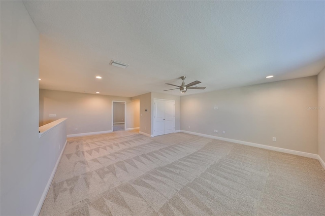 empty room featuring a textured ceiling, recessed lighting, light carpet, visible vents, and baseboards