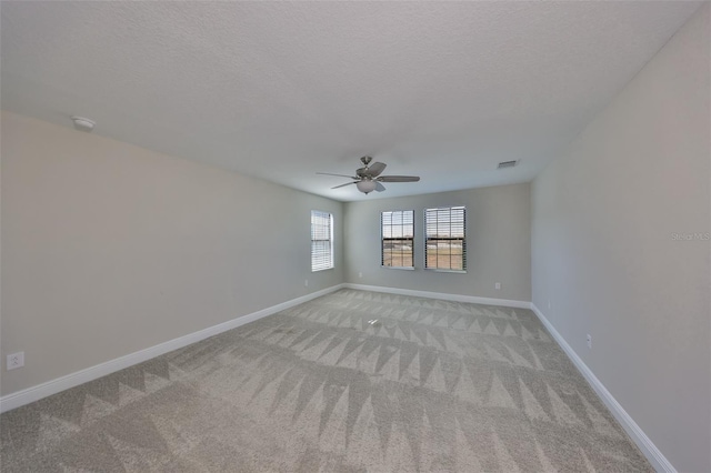 spare room featuring visible vents, a textured ceiling, light colored carpet, and baseboards