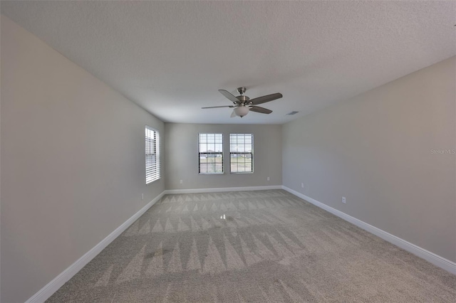 spare room with light carpet, ceiling fan, a textured ceiling, and baseboards