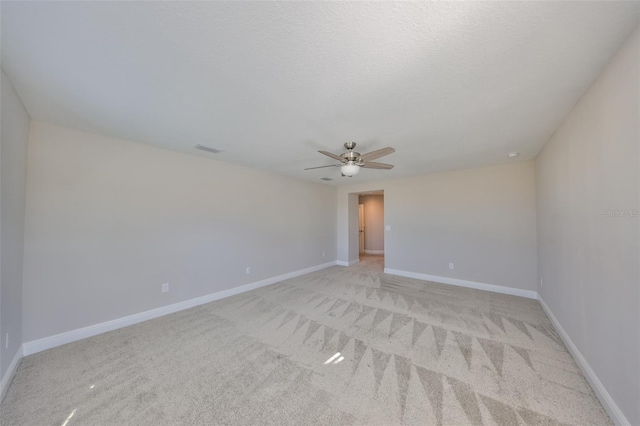 unfurnished room featuring a textured ceiling, ceiling fan, light colored carpet, visible vents, and baseboards