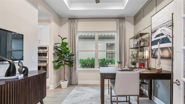 office area featuring ornamental molding, a raised ceiling, and light wood-type flooring