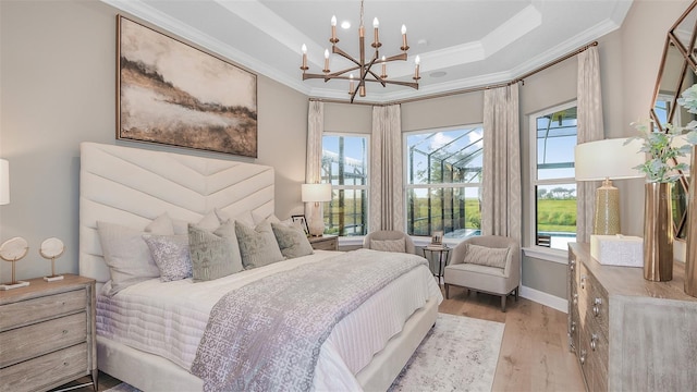 bedroom with crown molding, a tray ceiling, light hardwood / wood-style floors, and a chandelier