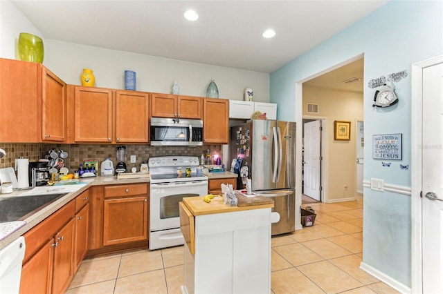 kitchen featuring light tile patterned floors, backsplash, stainless steel appliances, and a center island