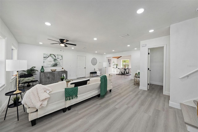 living area with light wood-type flooring, visible vents, baseboards, and recessed lighting