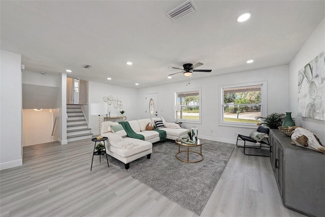 living room with stairway, visible vents, and light wood finished floors