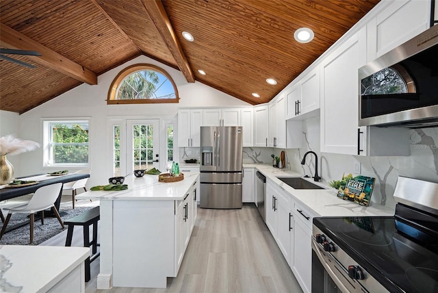 kitchen featuring tasteful backsplash, appliances with stainless steel finishes, a healthy amount of sunlight, a sink, and wooden ceiling