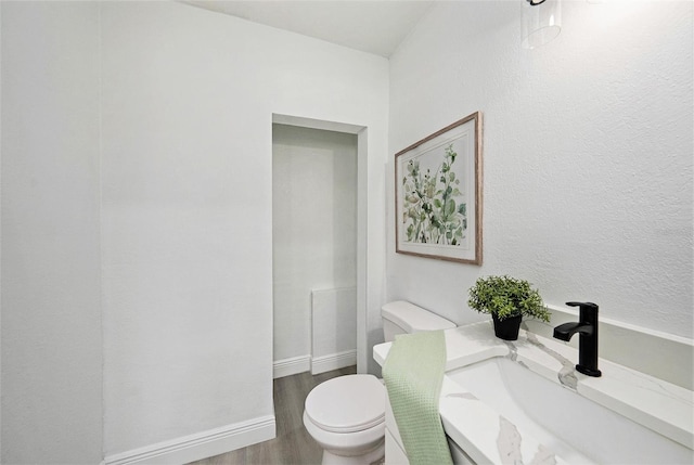 bathroom with baseboards, vanity, toilet, and wood finished floors