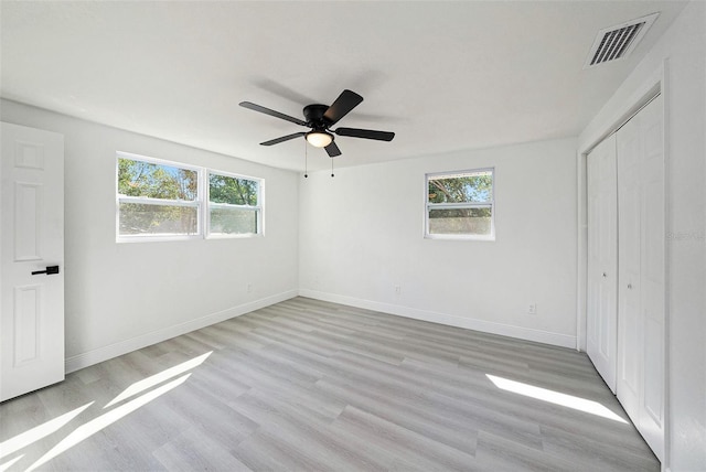 unfurnished bedroom with light wood-style floors, baseboards, multiple windows, and visible vents