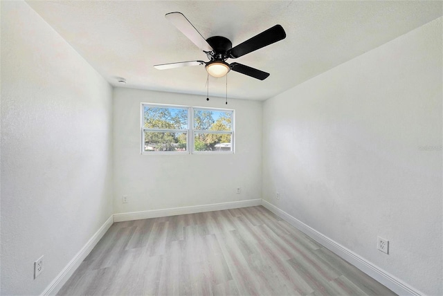 empty room featuring light wood-type flooring, baseboards, and a ceiling fan