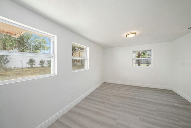 unfurnished room with light wood-style flooring and baseboards