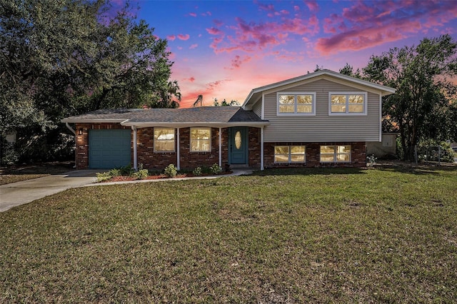 tri-level home with concrete driveway, brick siding, a lawn, and an attached garage