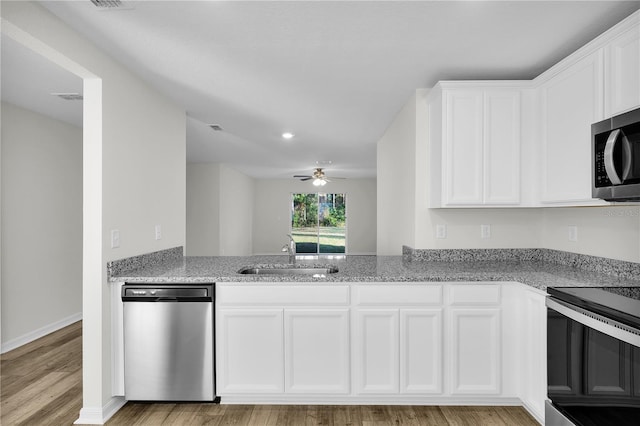 kitchen featuring sink, white cabinetry, light stone counters, stainless steel appliances, and light hardwood / wood-style floors