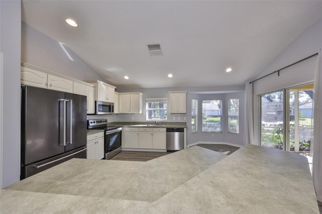 kitchen featuring white cabinetry, appliances with stainless steel finishes, sink, and lofted ceiling