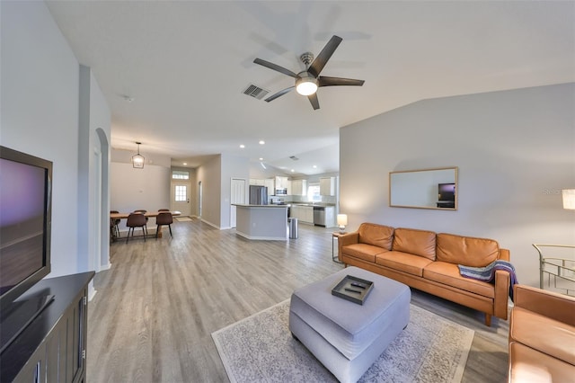 living room with ceiling fan, lofted ceiling, and light hardwood / wood-style flooring