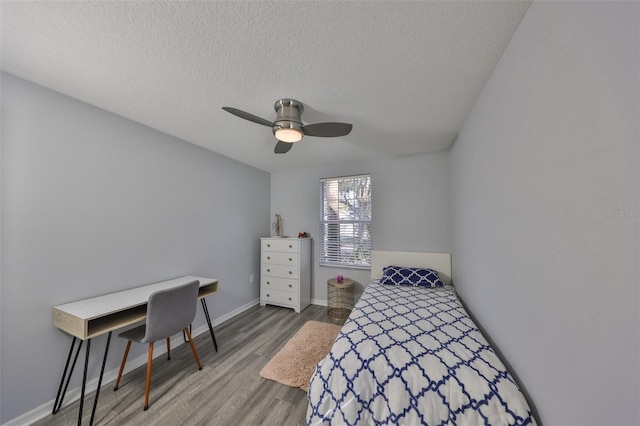 bedroom featuring ceiling fan, wood-type flooring, and a textured ceiling