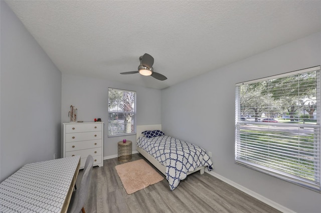 bedroom with hardwood / wood-style flooring, ceiling fan, and a textured ceiling