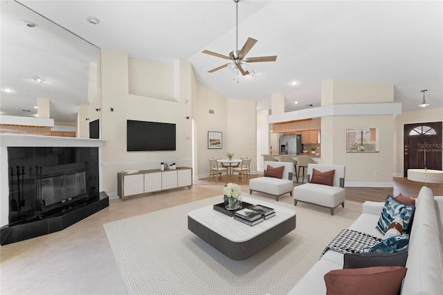 living room with high vaulted ceiling, a tile fireplace, and ceiling fan