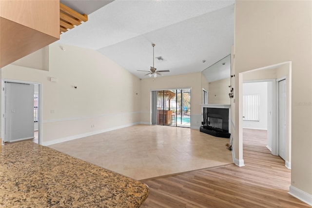 unfurnished living room with light hardwood / wood-style flooring, high vaulted ceiling, and ceiling fan