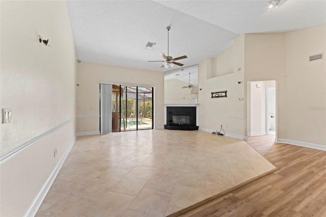 unfurnished living room with a textured ceiling, high vaulted ceiling, light hardwood / wood-style floors, and ceiling fan