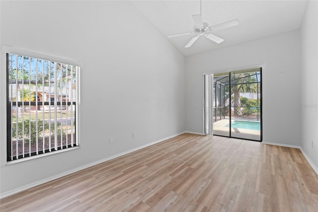 unfurnished room featuring ceiling fan, high vaulted ceiling, light hardwood / wood-style floors, and a textured ceiling