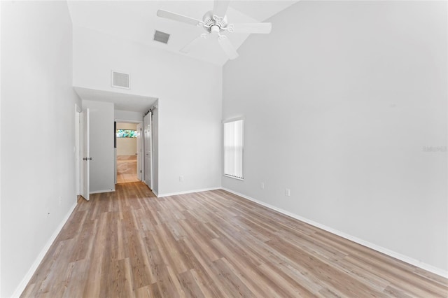 empty room featuring high vaulted ceiling, ceiling fan, and light wood-type flooring