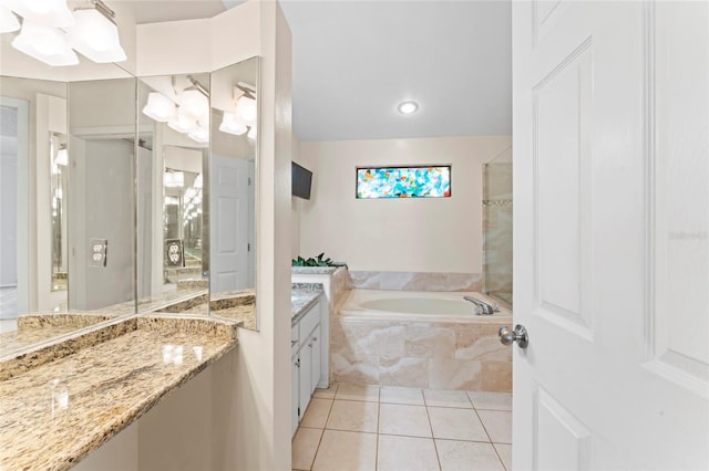 bathroom featuring tiled tub, vanity, and tile patterned floors