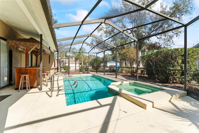 view of pool featuring a bar, an in ground hot tub, a patio area, and glass enclosure