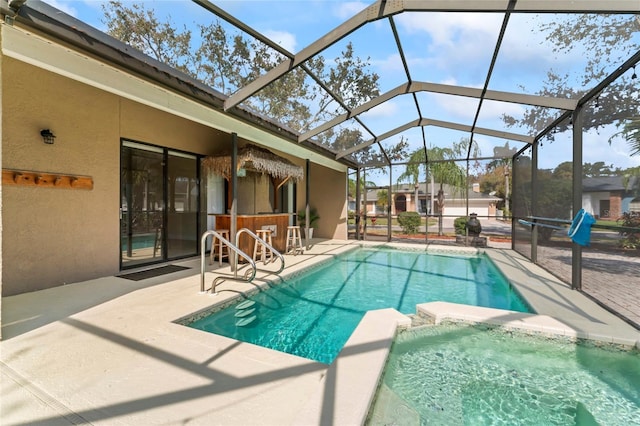 view of pool featuring glass enclosure, an outdoor bar, and a patio area