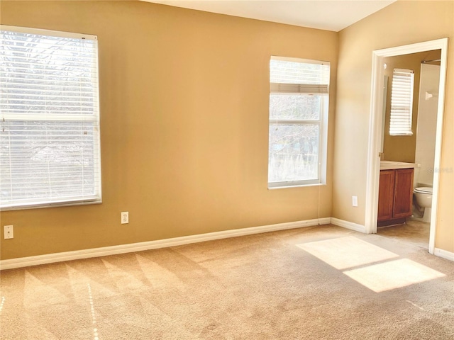 unfurnished bedroom with connected bathroom and light carpet