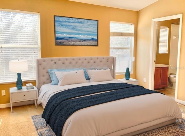 bedroom with ensuite bathroom and light colored carpet