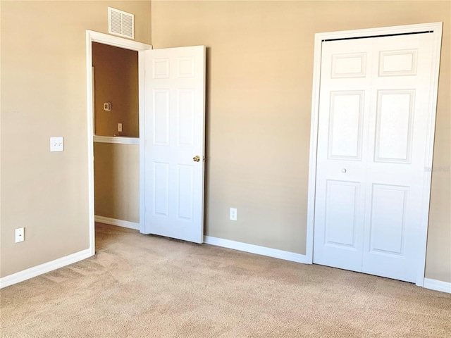 unfurnished bedroom with light colored carpet and a closet