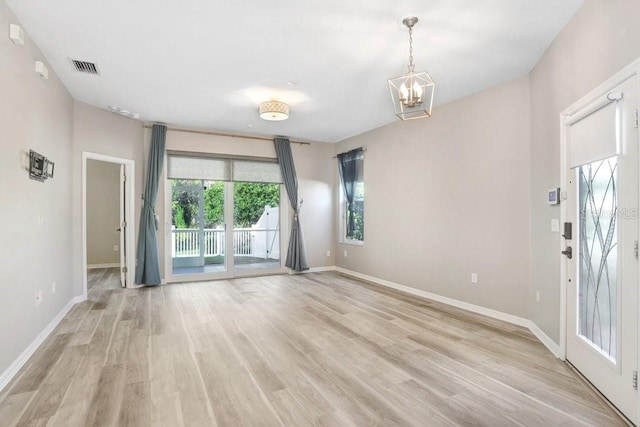 unfurnished room featuring a chandelier and light hardwood / wood-style flooring