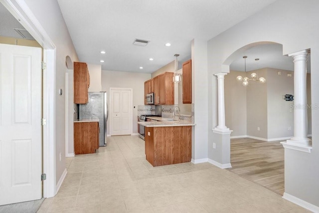 kitchen featuring ornate columns, appliances with stainless steel finishes, sink, and pendant lighting