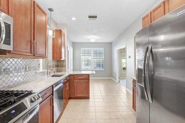 kitchen with sink, appliances with stainless steel finishes, light tile patterned flooring, decorative light fixtures, and kitchen peninsula