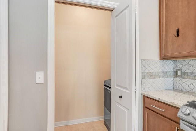 kitchen featuring stainless steel gas stove, tasteful backsplash, and light stone countertops