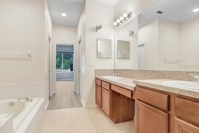 bathroom with tile patterned flooring, vanity, and tiled tub